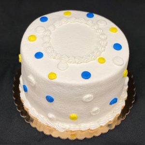 Round cake decorated with white frosting and blue and yellow polka dots