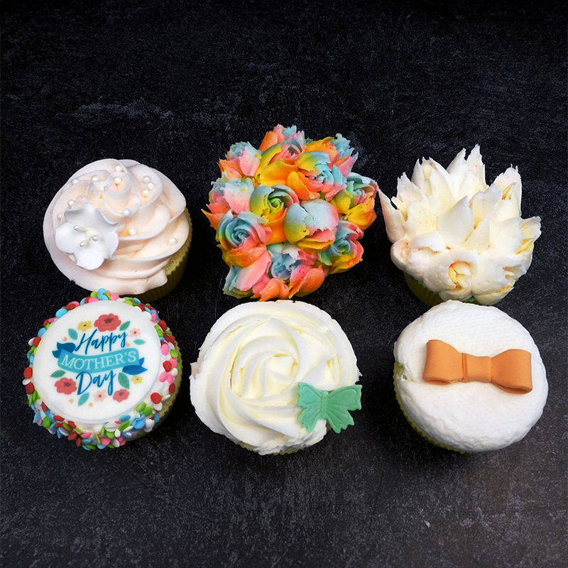 A picture of a set of six beautifully decorated Mother's Day-themed cupcakes.